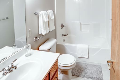 A white toilet is in a bathroom with a white sink.