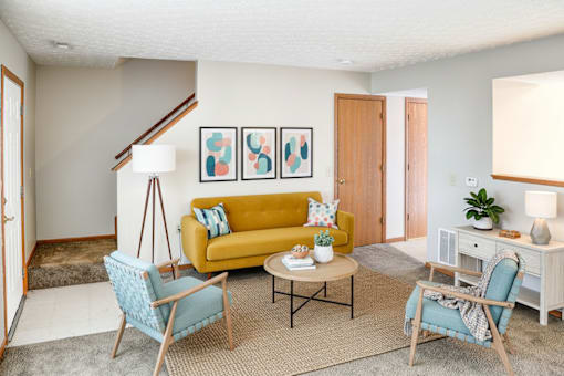 A living room with a yellow couch and blue chairs.