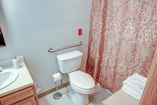 A white toilet with a towel rack and a sink in a bathroom.