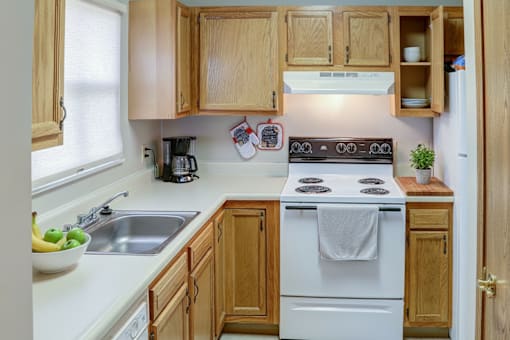 A kitchen with wooden cabinets and a white stove top oven.