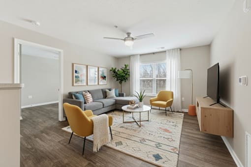 A living room with a couch, chairs, and a television.