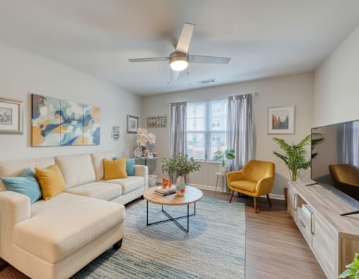 A living room with a white couch, a yellow chair, and a painting on the wall.