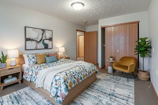A bedroom with a bed, a chair, and a painting on the wall.