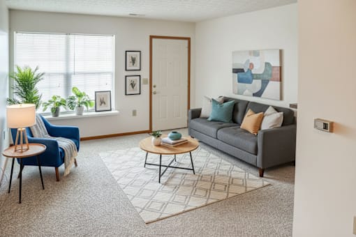 A living room with a grey couch, a blue chair, a wooden coffee table, and a rug.