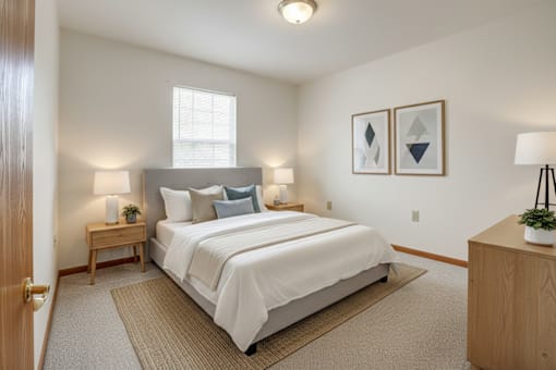 A bedroom with a large bed, two nightstands, and a window.