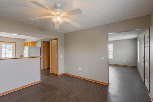 A room with a ceiling fan and wooden flooring.