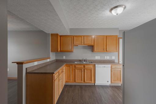 A kitchen with wooden cabinets and a white dishwasher.