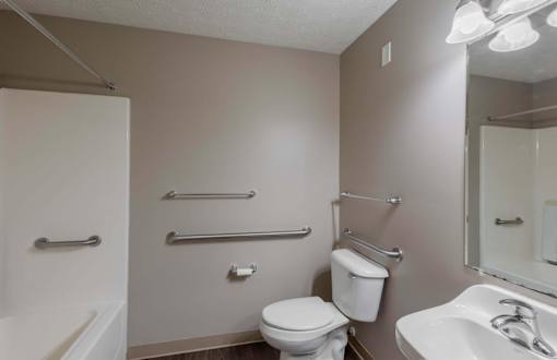A white toilet sits in a bathroom next to a sink and a shower.