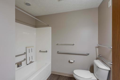 A white toilet sits next to a white bathtub in a small bathroom.