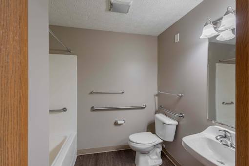 A small bathroom with a toilet, sink, and towel racks.