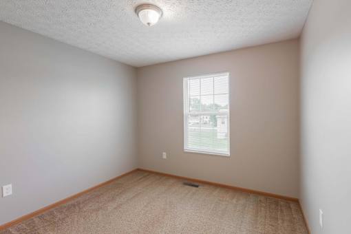 A room with a window and a carpeted floor.