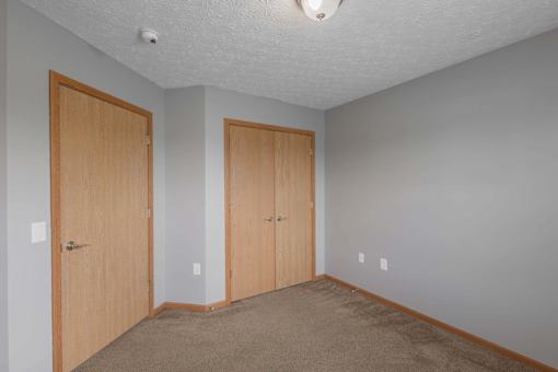 A room with two doors and carpeted floor.
