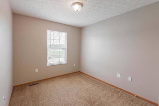 A room with a carpeted floor and a window.