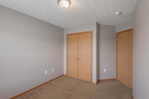A room with two doors and carpeted floor.
