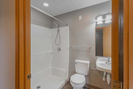 A white toilet is in a bathroom with a walk-in shower.