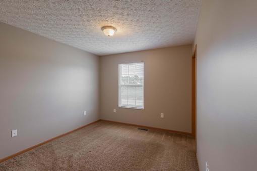 A room with a carpeted floor and a window.