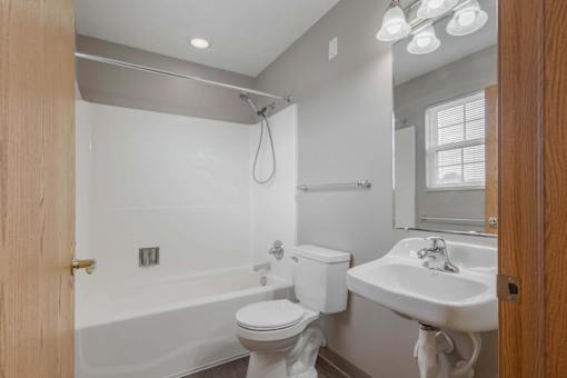 A white toilet sits next to a white sink in a bathroom.