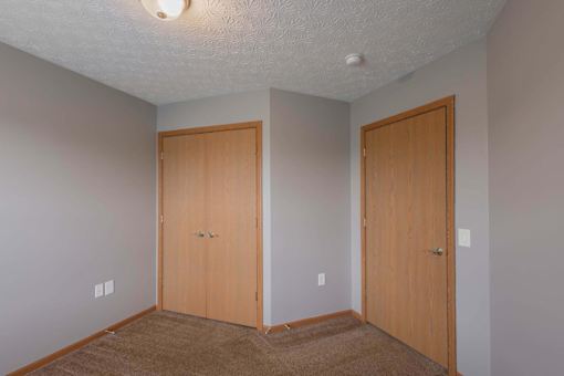 Two wooden doors in a room with carpeted floor.