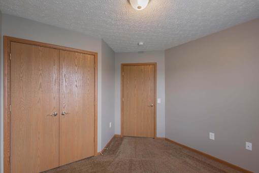 A room with two wooden doors and a carpeted floor.