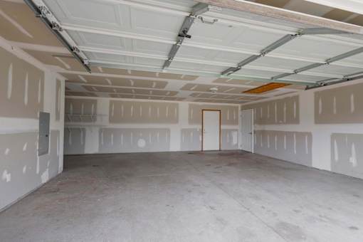 A spacious garage with a door and walls covered in drywall.
