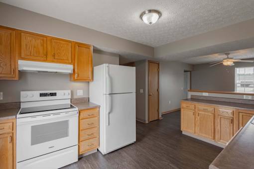 A kitchen with white appliances and wooden cabinets.