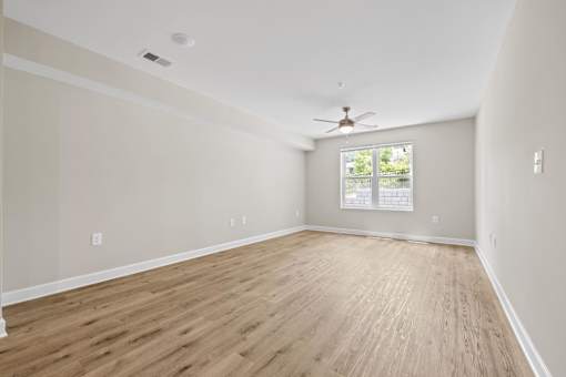 Empty room with wooden floor and ceiling fan.