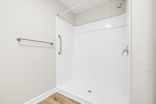 A white shower stall with a glass door and a white wall.