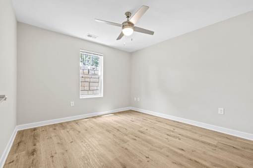 A room with a ceiling fan and a window with a white frame.