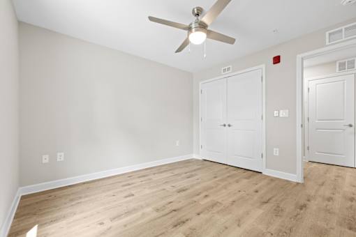 A room with a ceiling fan and three doors.