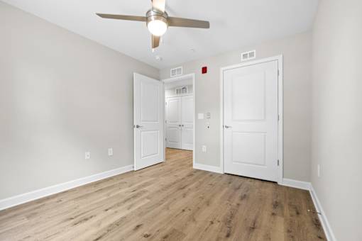 A room with a ceiling fan and wooden flooring.