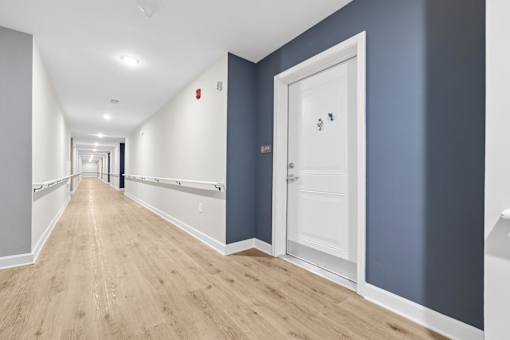 A long hallway with a white door on the right.