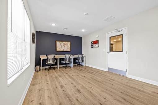 A room with a desk and chairs in it.