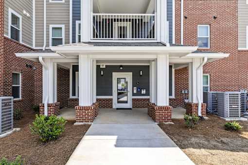 A brick building with a white entrance and a balcony.