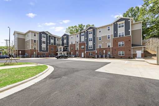 A large apartment complex with a parking lot in front.
