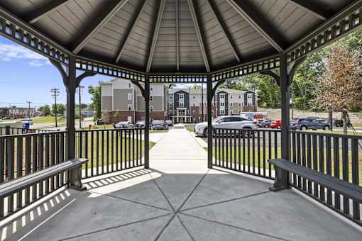 A gazebo with a black railing and a concrete floor.