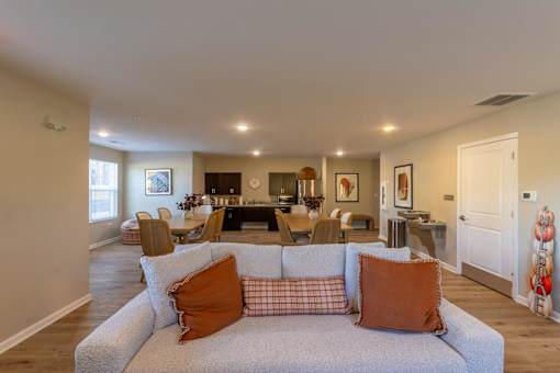 A living room with a grey couch and orange pillows.