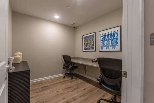 A room with two chairs and two framed pictures on the wall.