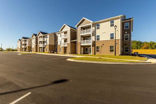 A row of apartment buildings with a parking lot in front.