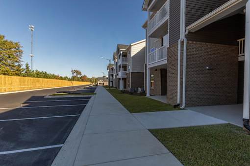 A long concrete walkway leads to a row of apartment buildings.