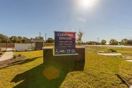 A sign for Clements Green is displayed in a grassy area.
