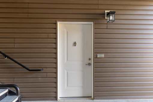 A white door with a black handle is on a brown wall.