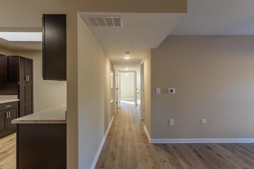 A long hallway with wood floors and white walls.