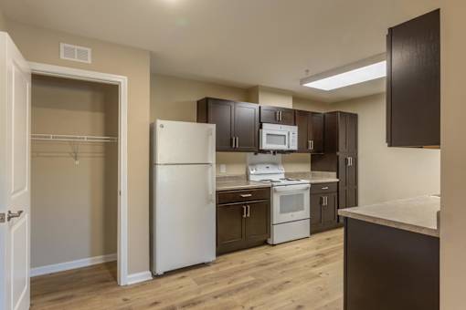 A kitchen with white appliances and brown cabinets.