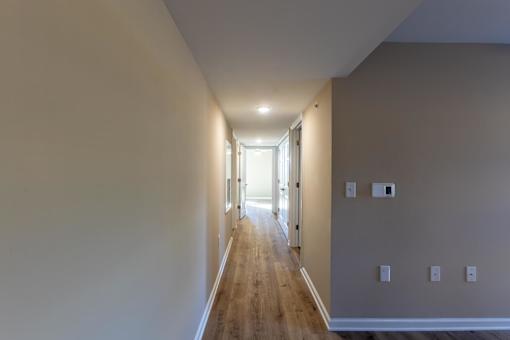 A long hallway with wooden floors and white walls.