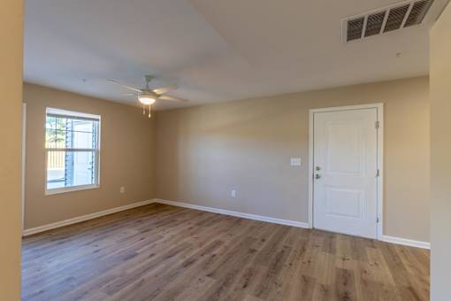 A room with a white door and a window with a fan on the ceiling.