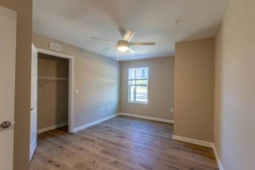 A room with a ceiling fan and a door leading to another room.