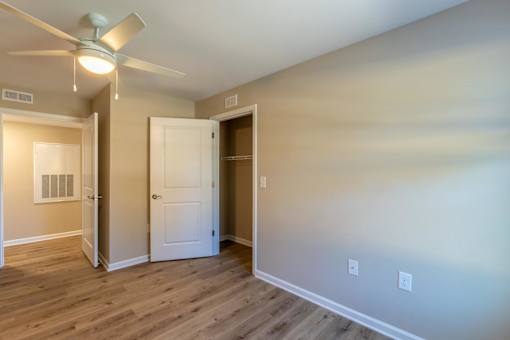 A room with a ceiling fan and a door leading to another room.