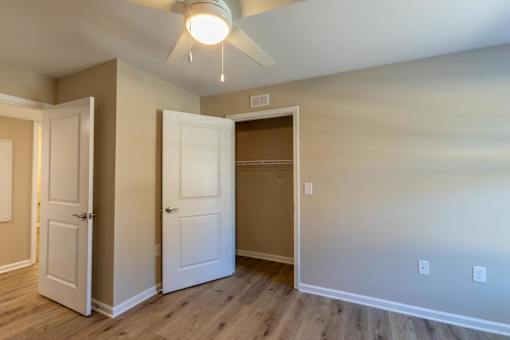 A room with a ceiling fan and three doors.