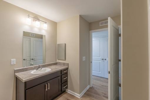 A bathroom with a sink, mirror, and lighting fixture.