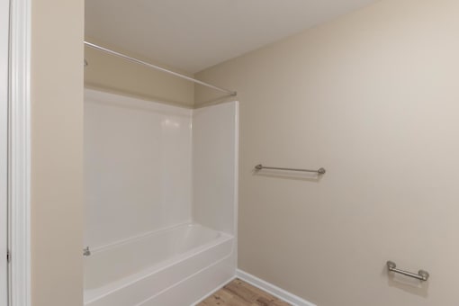 A white bathtub in a small bathroom.
